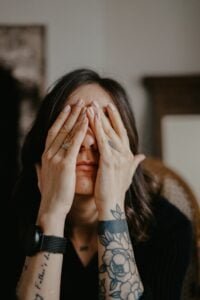 woman with hands over her face in overwhelm